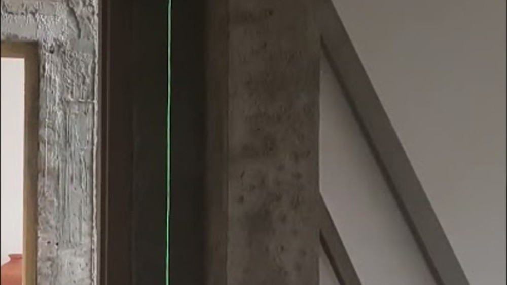 Laser level line checked against a concrete column on site