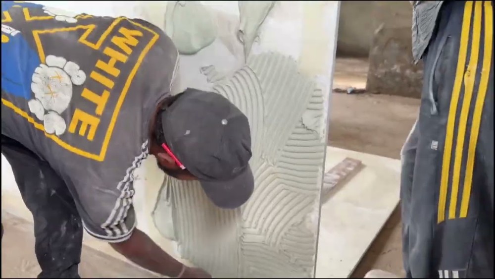 Adhesive being combed onto a slab of Italian marble before laying